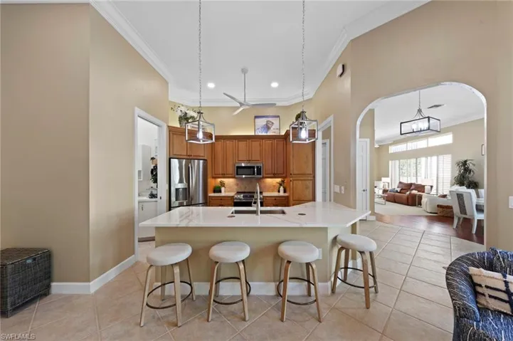 Kitchen featuring open floor plan, appliances with stainless steel finishes, brown cabinetry, a kitchen breakfast bar, and pendant lighting