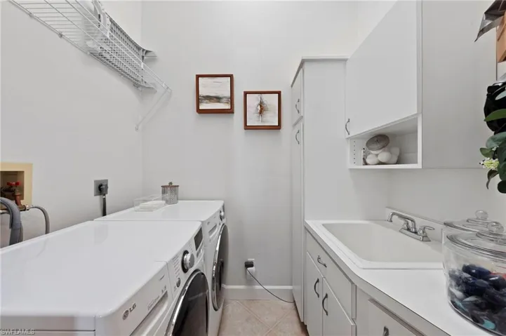 Washroom featuring light tile patterned floors, cabinet space, and washer and clothes dryer
