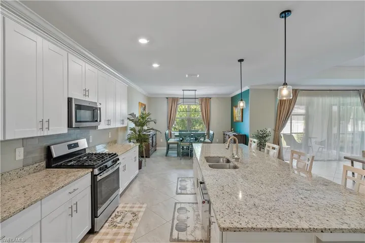 Kitchen featuring ornamental molding, a large island, stainless steel appliances, and sink