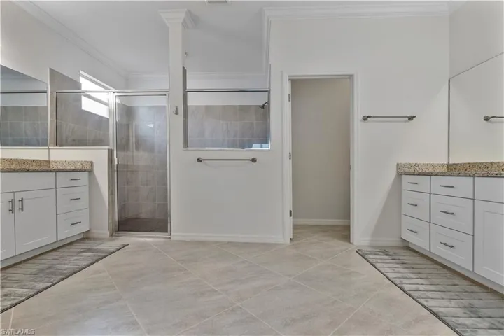 Bathroom featuring ornamental molding, a shower with shower door, and vanity