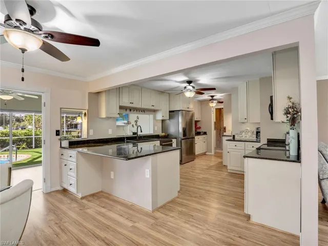 Kitchen featuring stainless steel appliances, ceiling fans, a peninsula with breakfast bar seating and crown molding