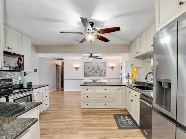 Kitchen with stainless steel appliances, a sink, a ceiling fan, a peninsula, and decorative backsplash