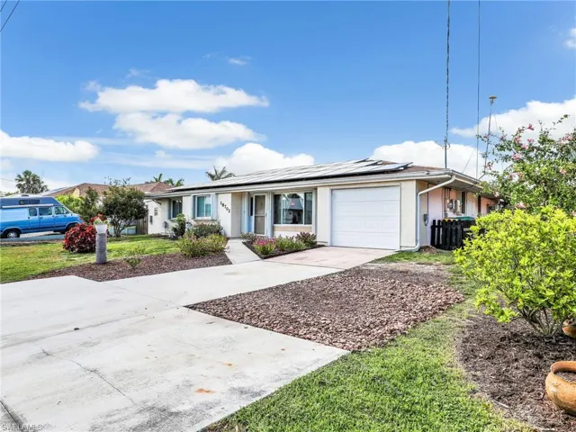 Single story home with an attached garage, concrete driveway, roof mounted solar panels, and stucco siding