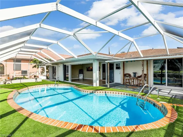 Swimming pool featuring a patio area, a yard, and glass enclosure