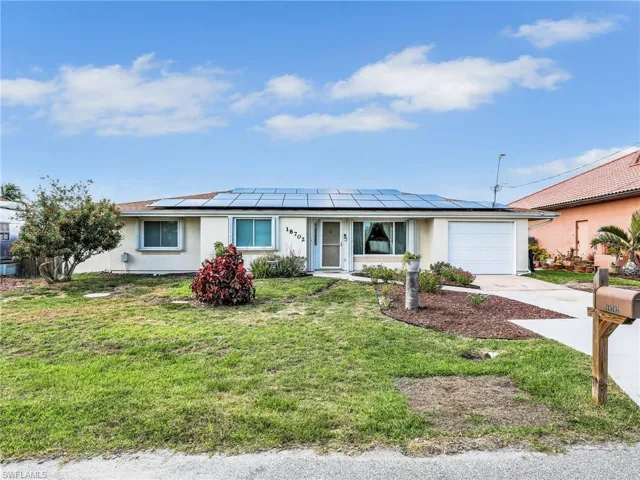 Ranch-style home featuring an attached garage, concrete driveway, roof mounted solar panels, with RV/Boat parking