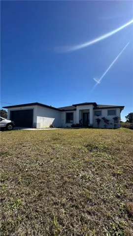 Rear view of house with stucco siding, a garage, and a yard