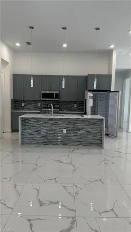 Kitchen featuring light stone counters, gray cabinetry, and decorative backsplash