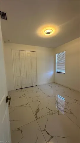 Unfurnished bedroom with light marble finish floors and a closet