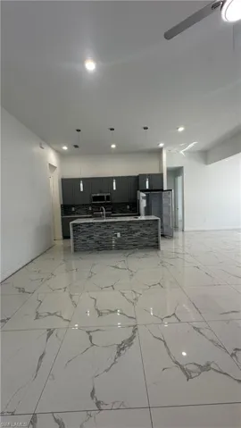 Kitchen featuring open floor plan, hanging light fixtures, a spacious island, and dark cabinets