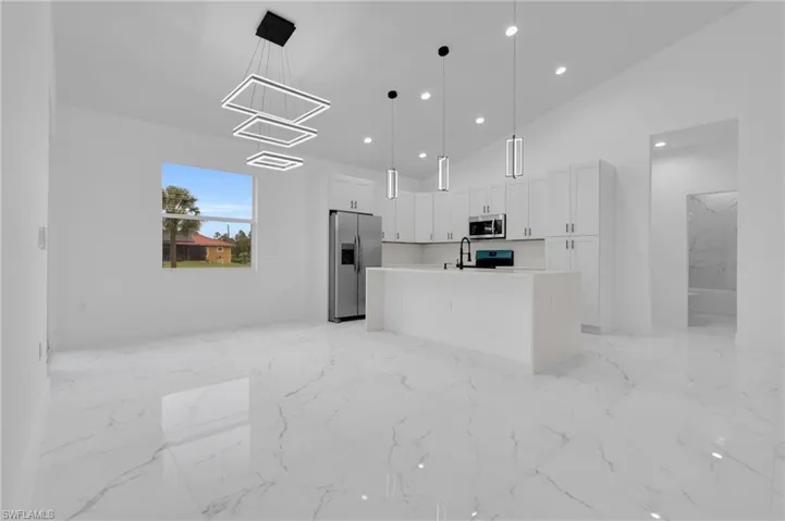 Dining area with modern light fixture, open to the kitchen island.