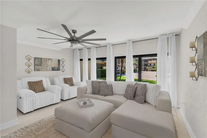 Living room with a textured wall, ornamental molding, and a ceiling fan