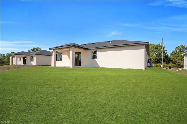 Back of property featuring stucco siding and a yard