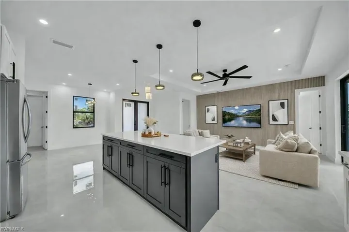 Kitchen with open floor plan, freestanding refrigerator, pendant lighting, a kitchen island, and finished concrete flooring