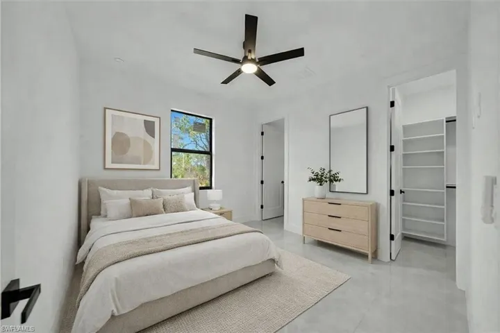 Bedroom featuring a spacious closet, a ceiling fan, and finished concrete floors