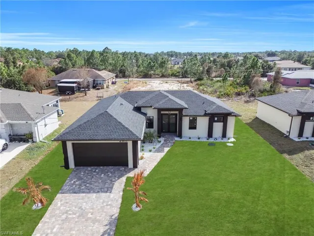 View of front of house with a shingled roof, a front yard, decorative driveway, stucco siding, and an attached garage