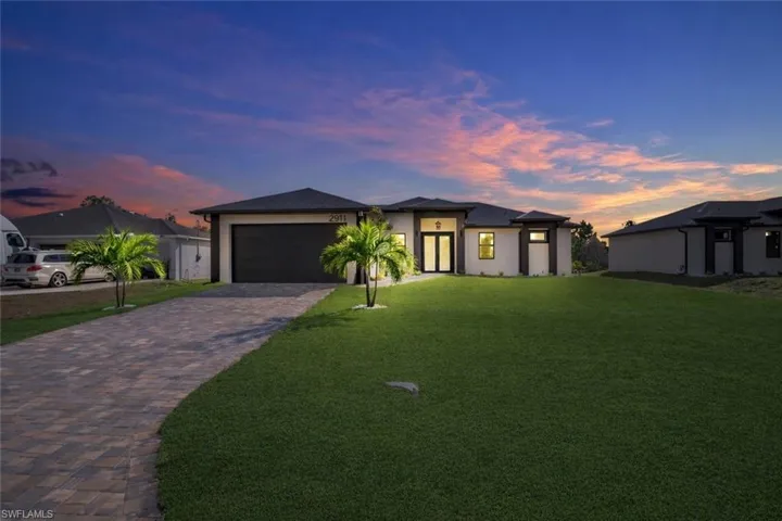 Prairie-style home featuring stucco siding, a yard, driveway, and a garage
