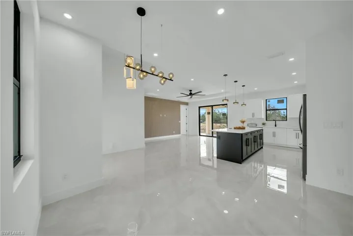 Dual tone kitchen featuring open floor plan, pendant lighting, a center island, two tone color scheme, and ceiling fan