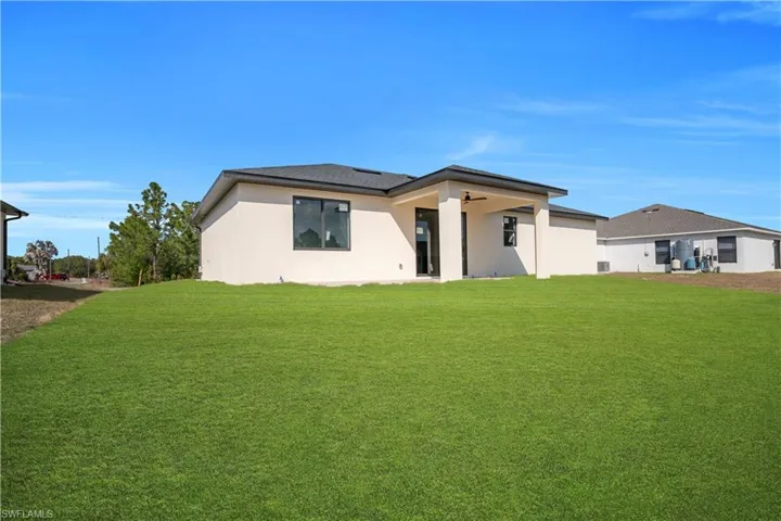 Back of property featuring a lawn, stucco siding, and a patio area