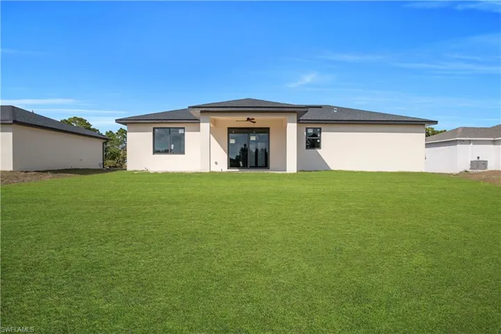 Rear view of property with a lawn and stucco siding