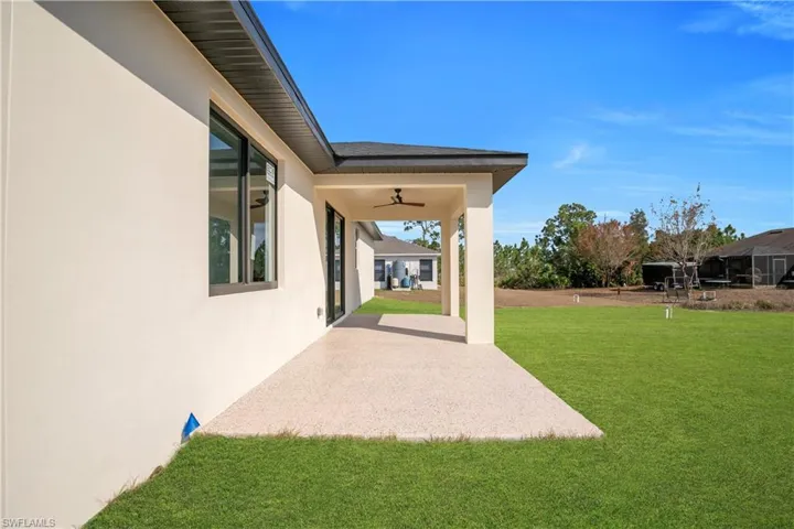 View of green lawn featuring a ceiling fan and a patio
