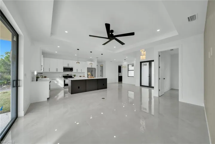 Unfurnished living room with recessed lighting, ceiling fan, and a raised ceiling