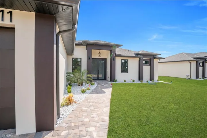 Doorway to property with stucco siding, a yard, and french doors