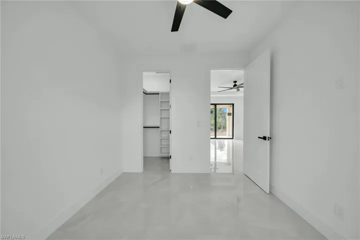 Unfurnished bedroom featuring a spacious closet and a ceiling fan