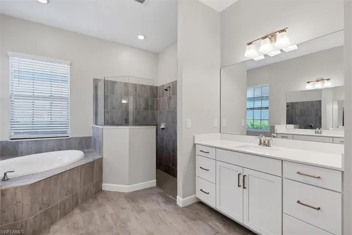 Full bathroom featuring vanity, a bath, and walk in shower