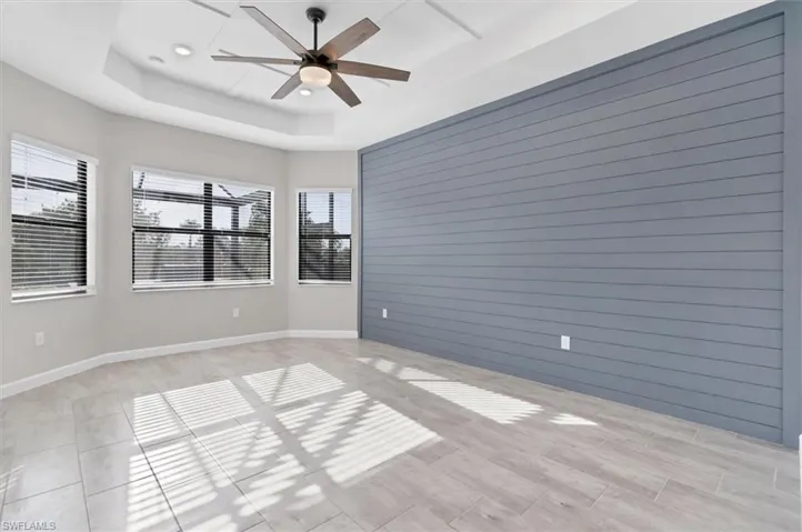 Unfurnished room with plenty of natural light, ceiling fan, a raised ceiling, light tile patterned flooring, and recessed lighting