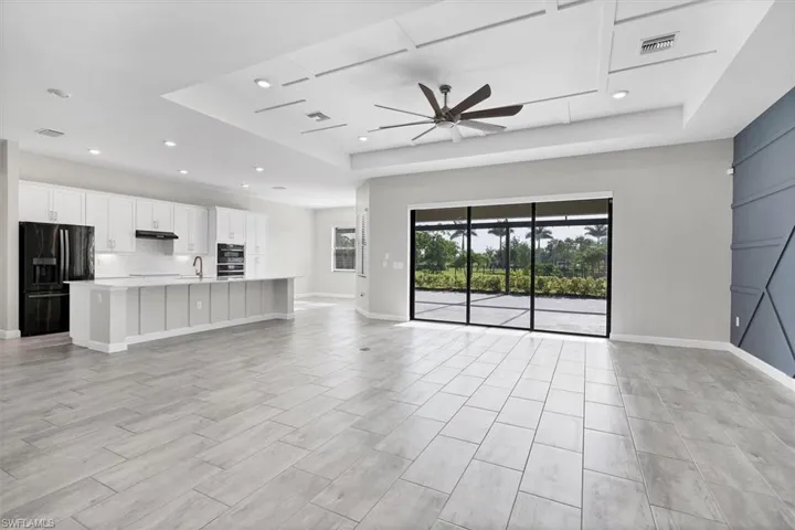 Unfurnished living room featuring a tray ceiling, ceiling fan, and recessed lighting