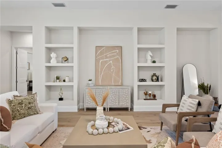 Living room with built in features and light hardwood / wood-style flooring