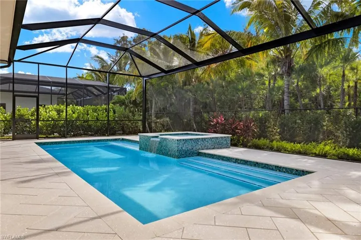 View of swimming pool featuring a patio, picture frame pool enclosure, and an in ground hot tub