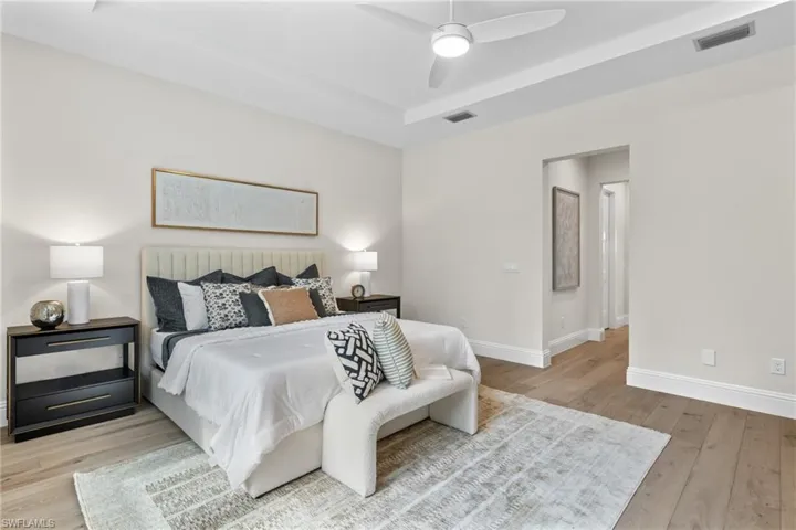 Bedroom with a raised ceiling, ceiling fan, and light hardwood / wood-style flooring