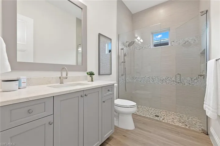 Bathroom with an enclosed shower, vanity, and toilet