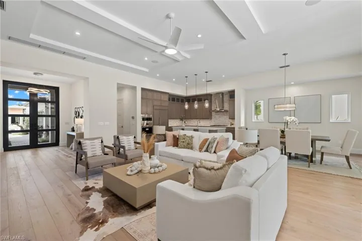 Living room featuring a healthy amount of sunlight, ceiling fan, light hardwood / wood-style flooring, and a raised ceiling