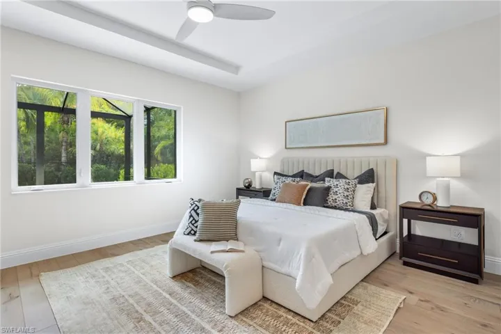 Bedroom featuring a tray ceiling, light hardwood / wood-style floors, and ceiling fan