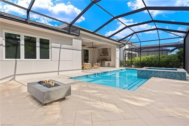 View of swimming pool featuring a lanai, an in ground hot tub, an outdoor fire pit, ceiling fan, and a patio