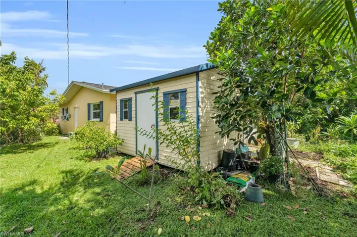 Rear view of property featuring a yard and a storage unit