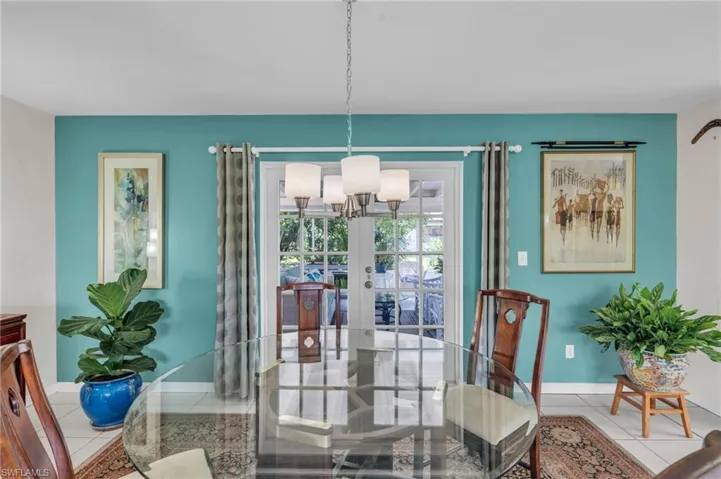 Tiled dining room with a notable chandelier and french doors