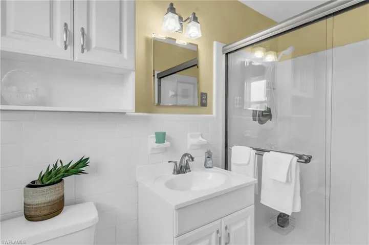 Bathroom featuring tile walls, vanity, toilet, and a shower with shower door