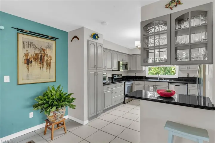 Kitchen with gray cabinetry, kitchen peninsula, sink, and stainless steel appliances