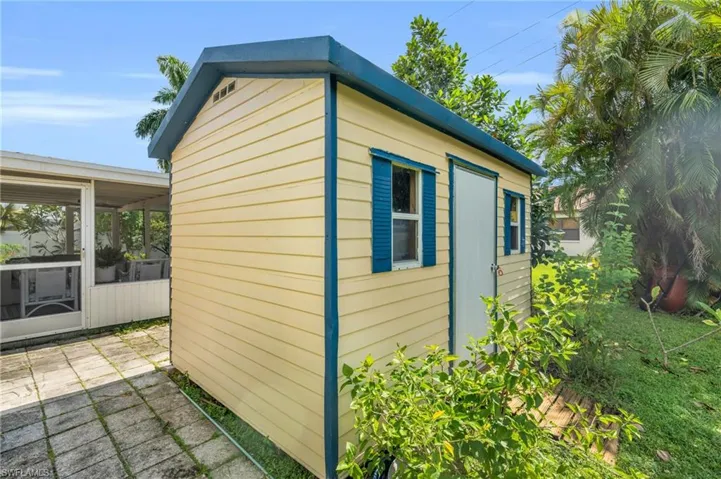 View of property exterior featuring an outbuilding, a sunroom, and a patio area