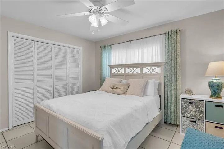 Tiled bedroom with ceiling fan and a closet