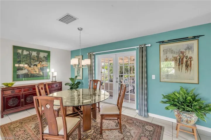Dining space with light tile patterned flooring, french doors, and a notable chandelier