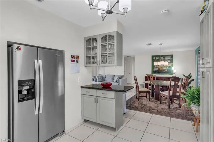 Kitchen with light tile patterned floors, white cabinets, stainless steel fridge with ice dispenser, and a chandelier