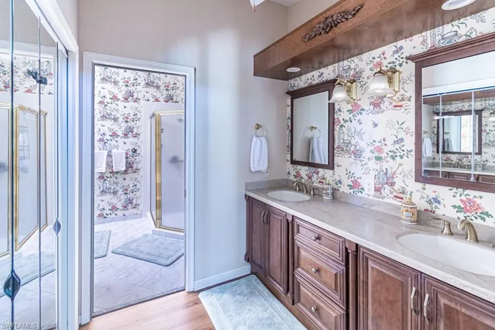 Full bath featuring wallpapered walls, a sink, and a shower stall