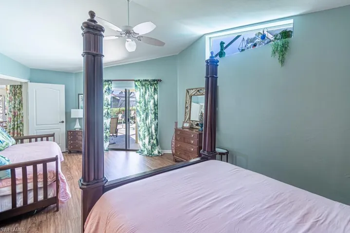 Bedroom featuring baseboards, access to outside, wood finished floors, a ceiling fan, and vaulted ceiling