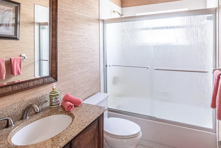 Bathroom featuring toilet, vanity, and enclosed tub / shower combo