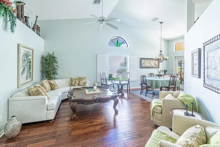 Living area featuring visible vents, high vaulted ceiling, wood finished floors, and a healthy amount of sunlight