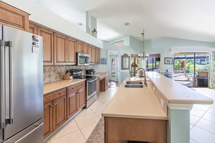 Kitchen featuring light tile patterned floors, a sink, appliances with stainless steel finishes, and brown cabinets